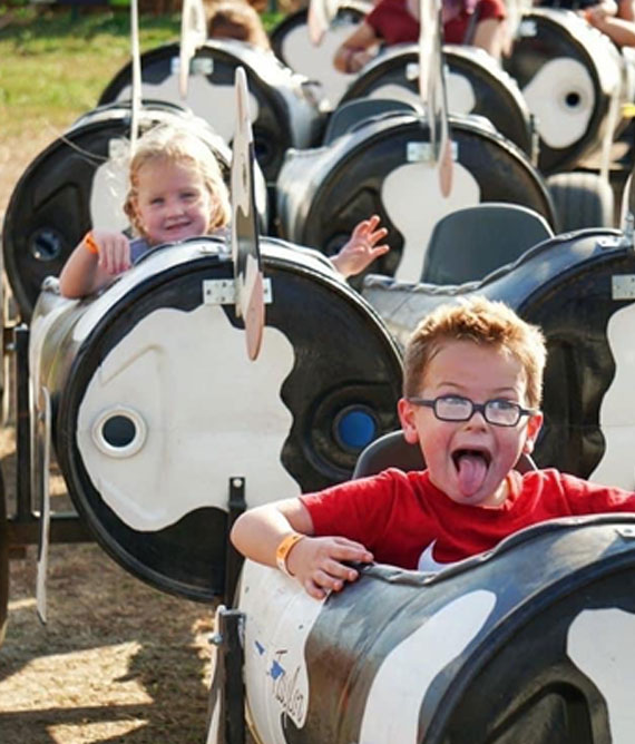 kids on cow train made of oil barrels